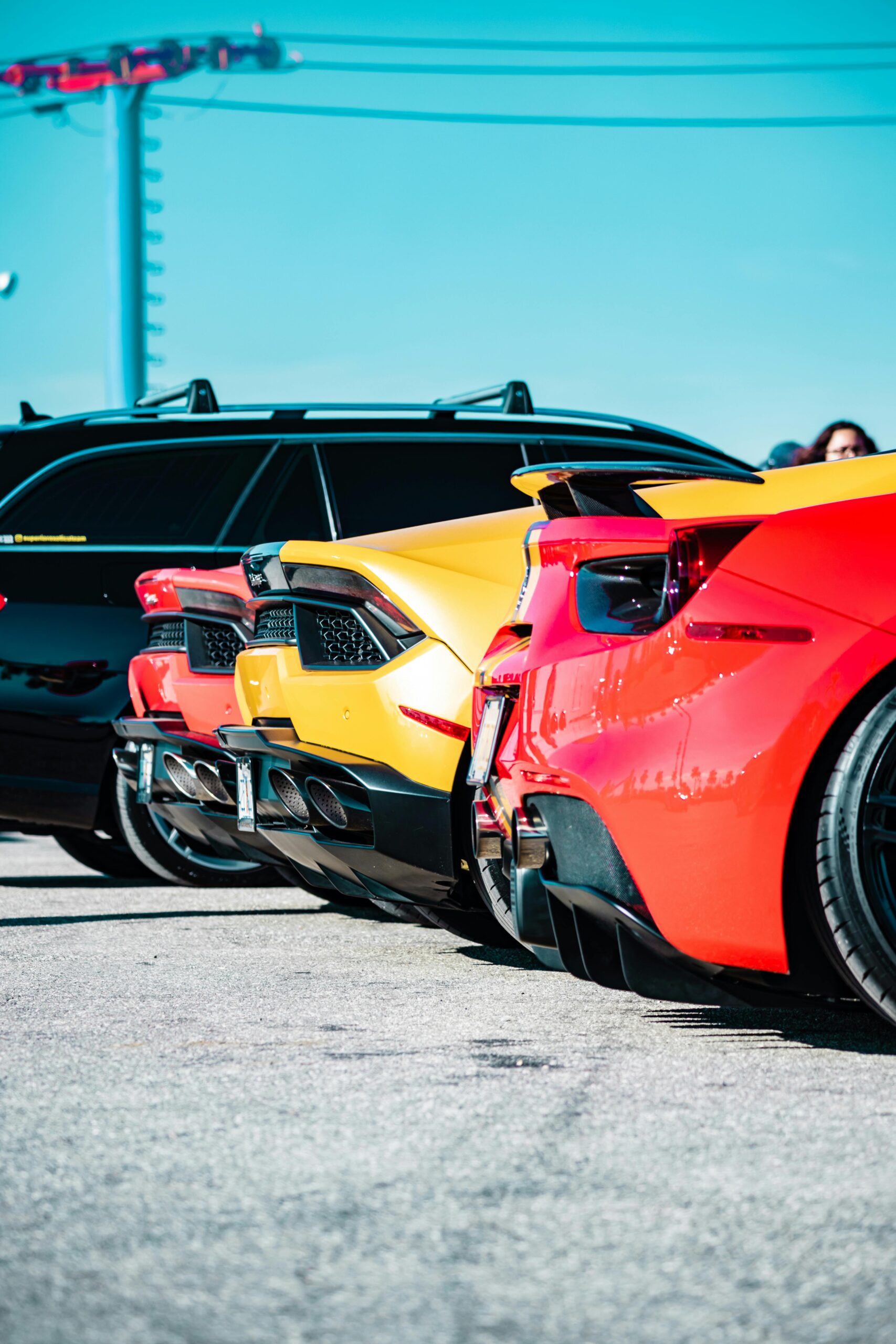 A striking lineup of luxury sports cars featuring different colors parked outdoors under clear skies.