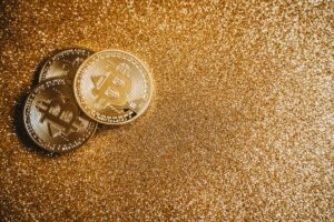 Shiny bitcoin coins placed on a glittery gold surface, symbolizing cryptocurrency wealth.